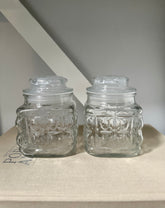 Two glass vintage jars on a linen book with neutral background