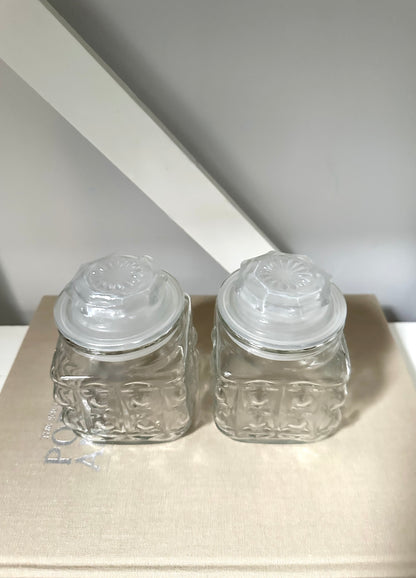 Two glass vintage jars on a linen book with neutral background