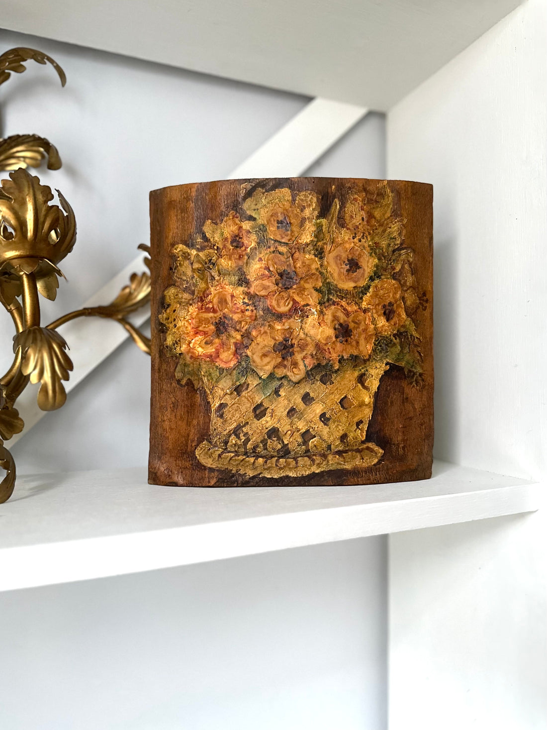 Decorative wooden art with floral design on a white shelf