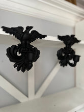 A pair of black cast iron eagle wall sconces mounted on a white wooden mantel shelf.