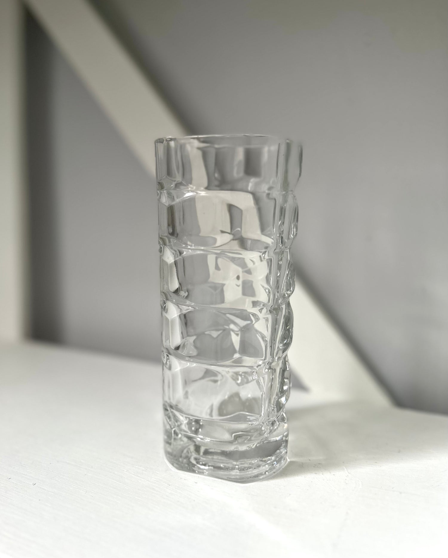 Clear textured glass vase on a light surface with a neutral background