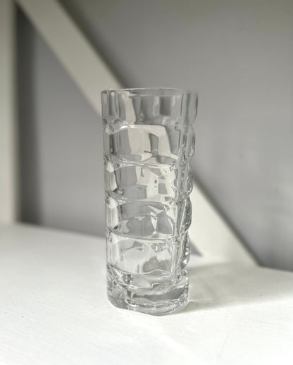Clear textured glass vase on a light surface with a neutral background