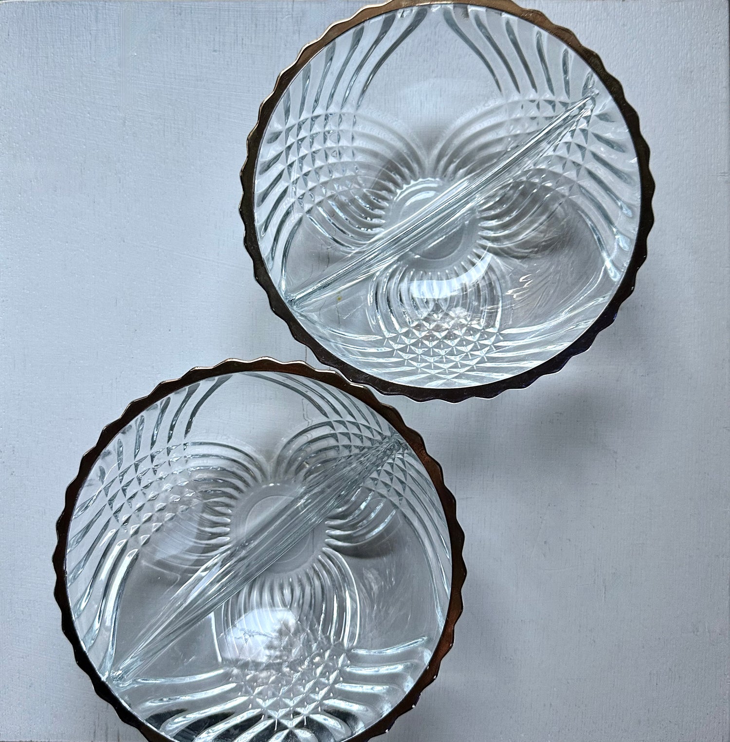 2 clear crystal bowls with metallic rim on white surface