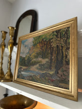 Framed landscape painting on a shelf with decorative items.