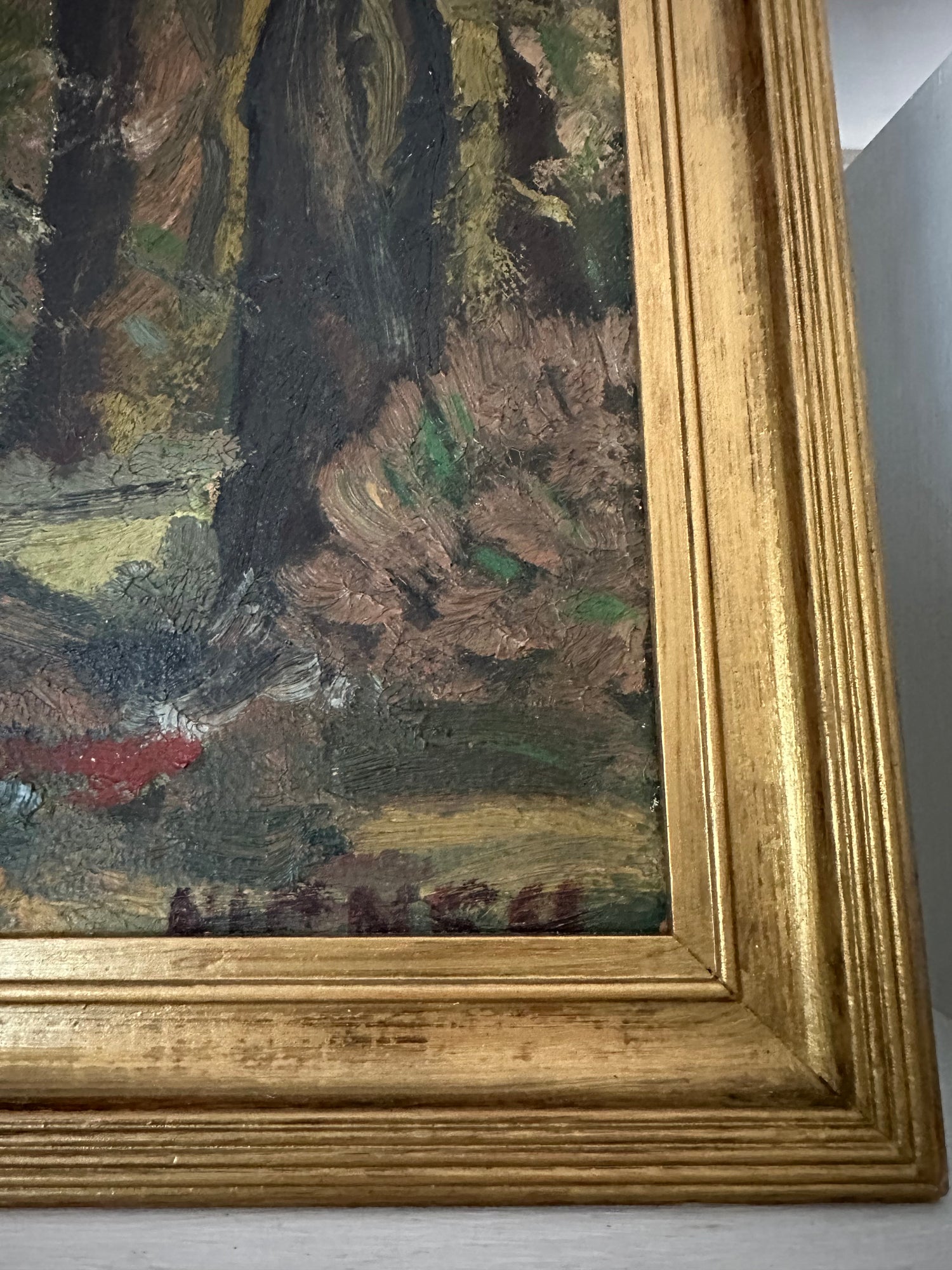 Close-up of a painting with a gold frame on a gray wall.