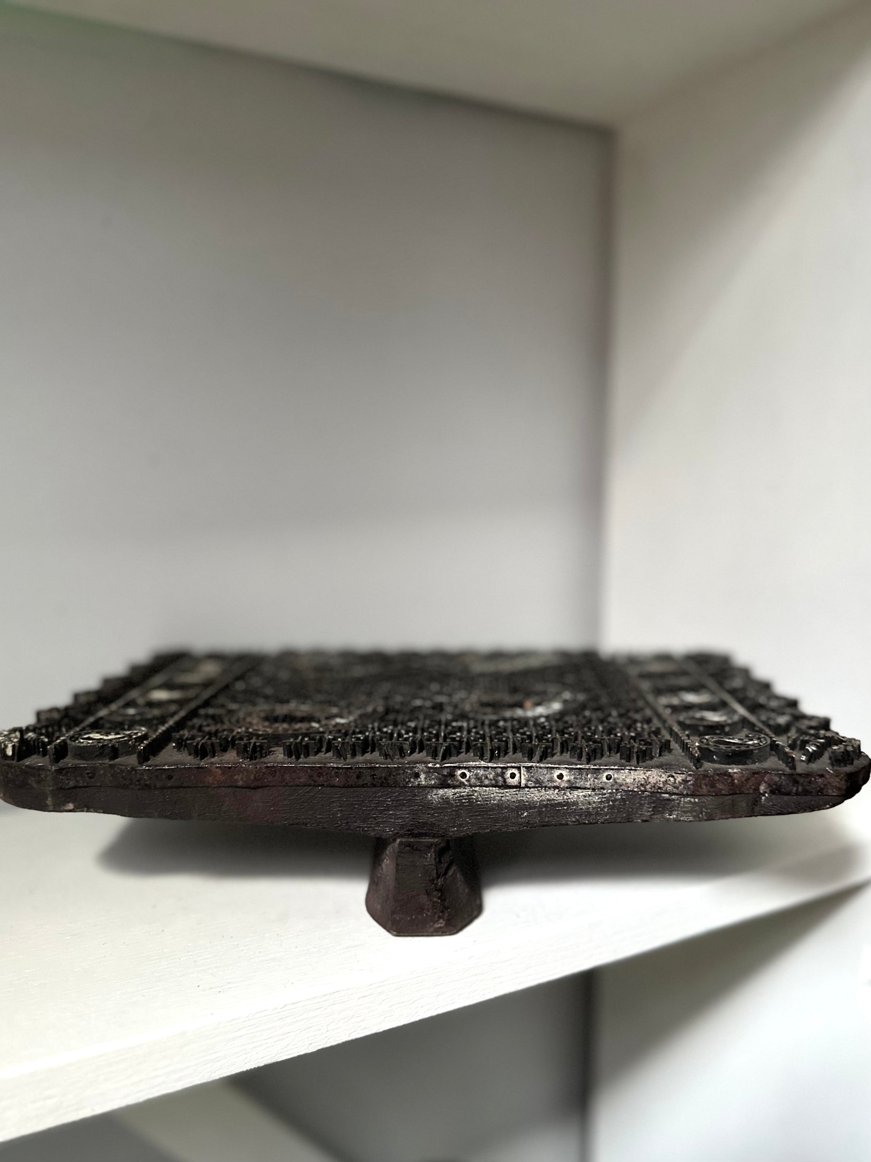 Dark metal object on a white surface with a neutral background