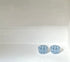 Two small light blue faceted glass cups or candle holders placed side by side on a white surface against a white background.
