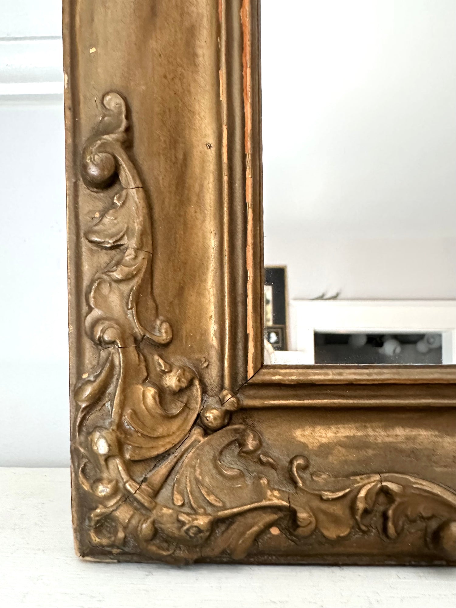 Decorative gold mirror with intricate designs on a white background