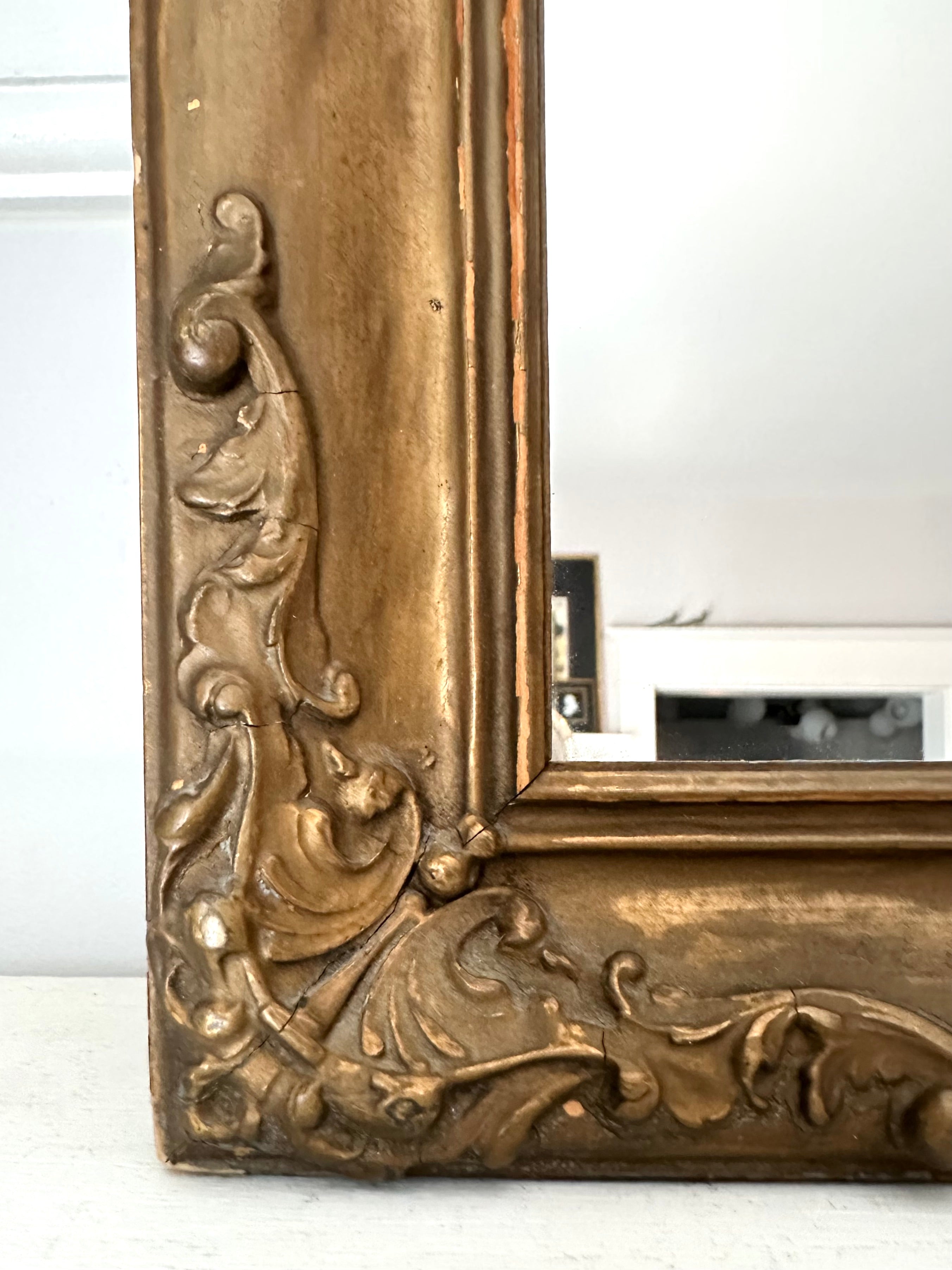 Decorative gold mirror with intricate designs on a white background