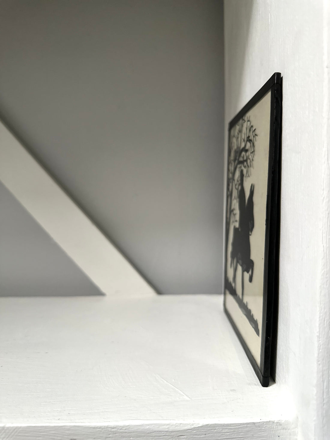 Framed artwork leaning against a white wall