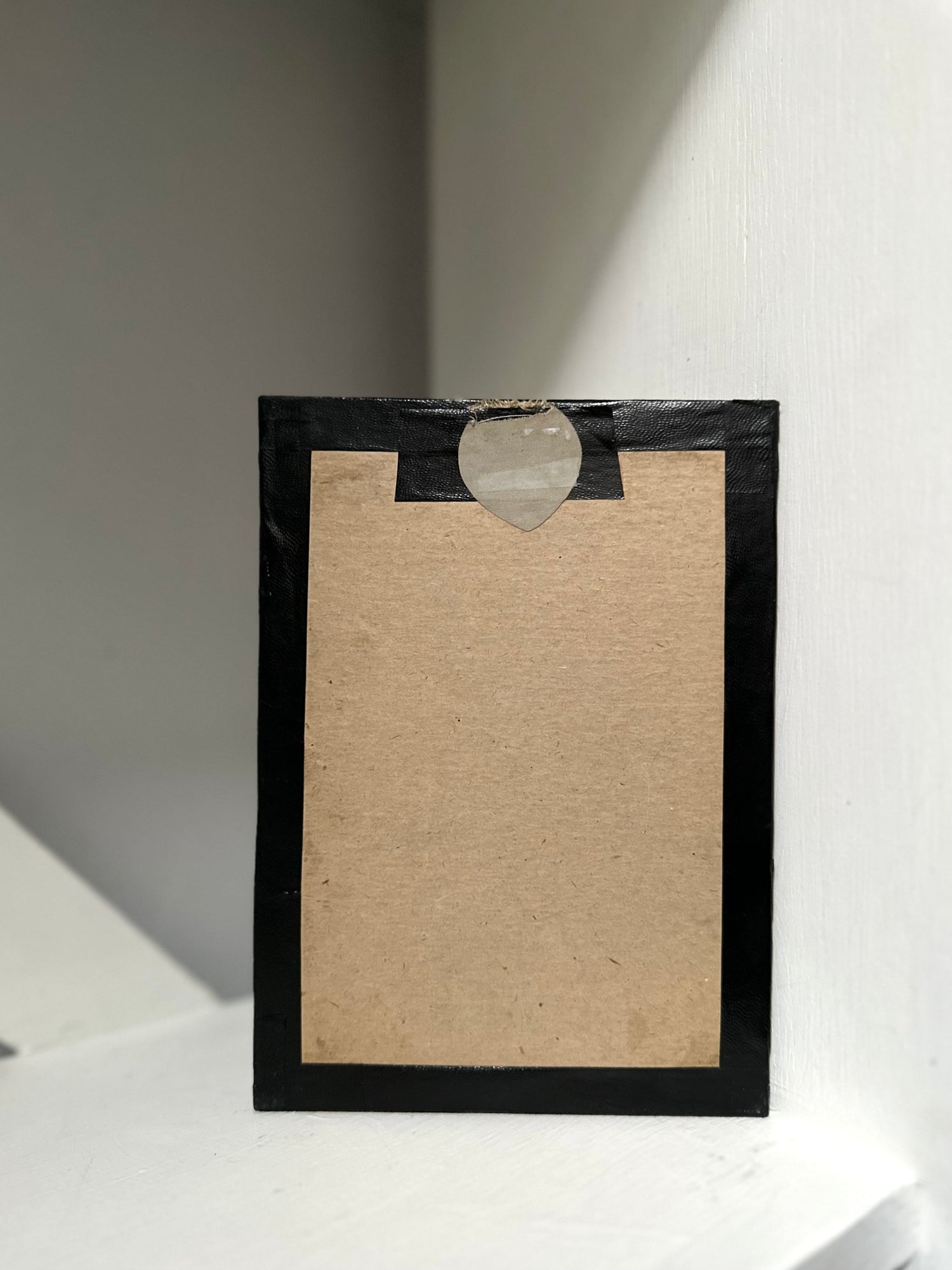 Black picture frame with a heart-shaped hole on a white background