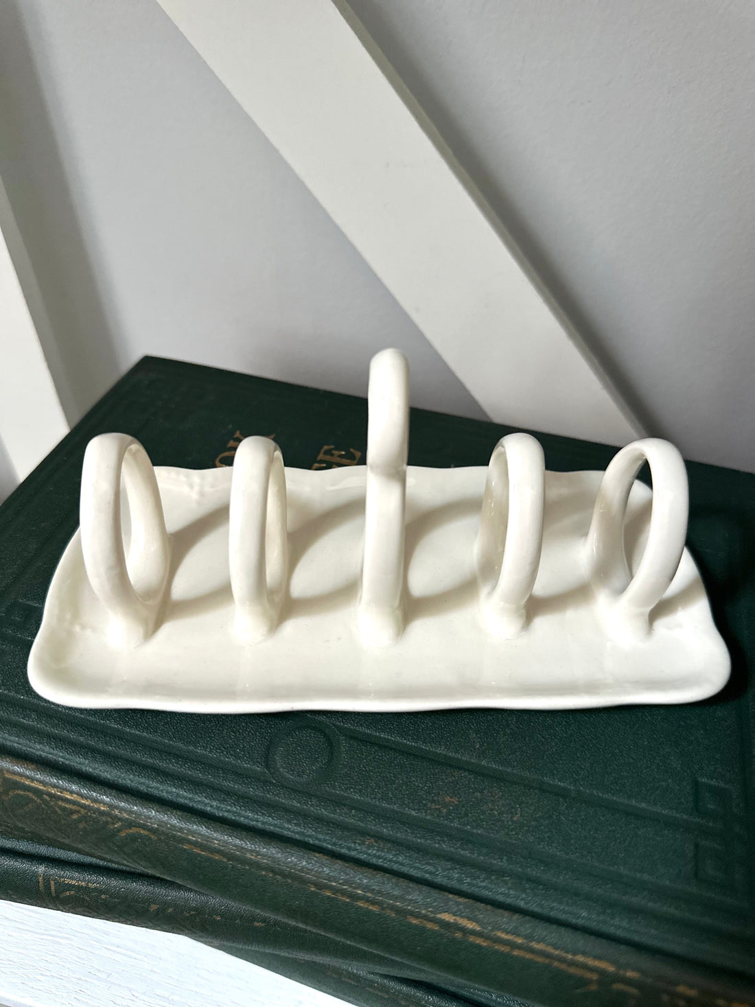 White ceramic dish drying rack on a dark surface with a light gray background