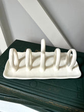 White ceramic dish drying rack on a dark surface with a light gray background