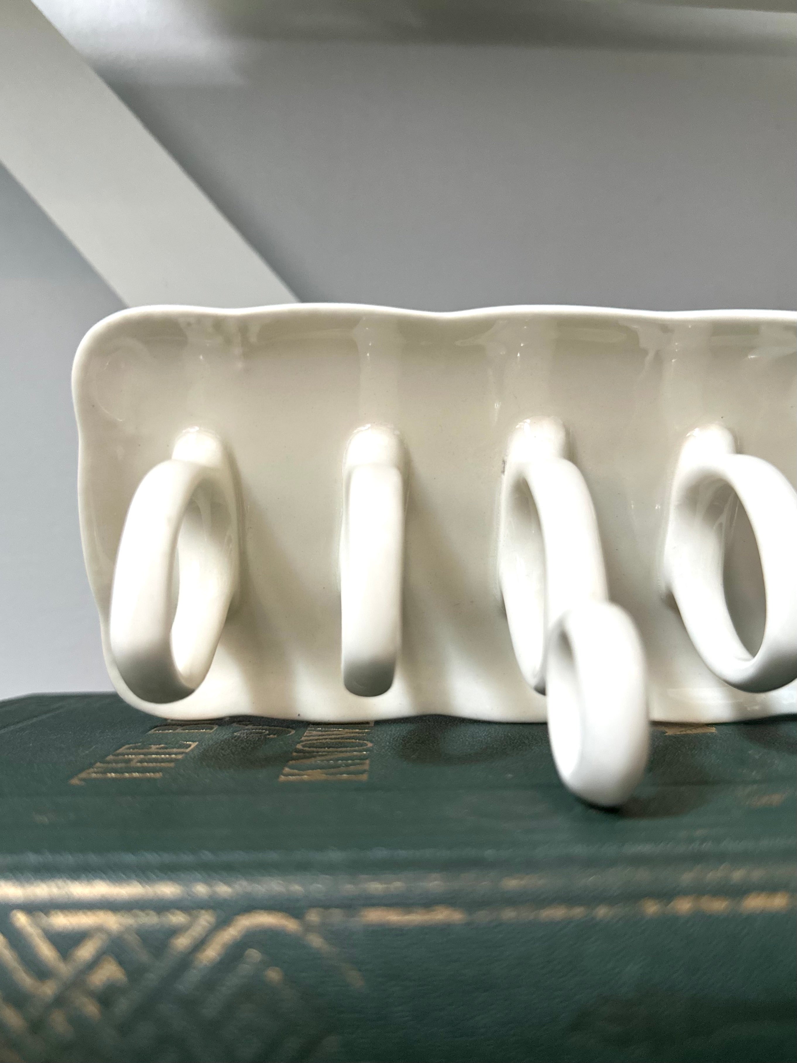 White ceramic rack with four hooks on a dark surface