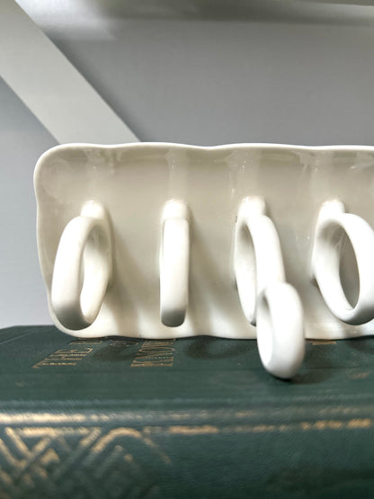 White ceramic rack with four hooks on a dark surface