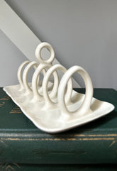 White ceramic toast rack on a dark surface with a gray background