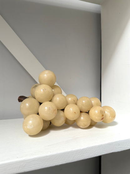 Bunch of beige grapes on a white surface with a gray background