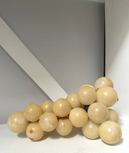 Beige decorative object resembling a cluster of grapes on a plain background