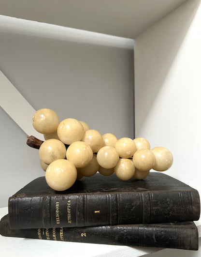 Decorative arrangement of beige spherical objects on black books against a neutral background
