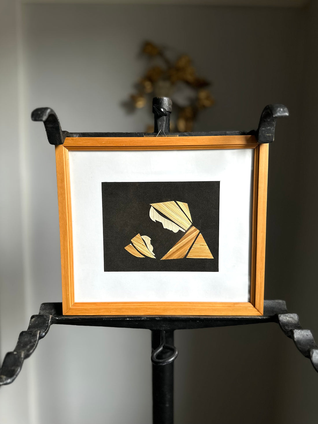 Framed artwork with geometric design on a stand against a neutral background