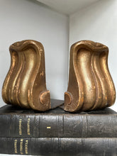 Gold decorative corbels on a black book against a white wall
