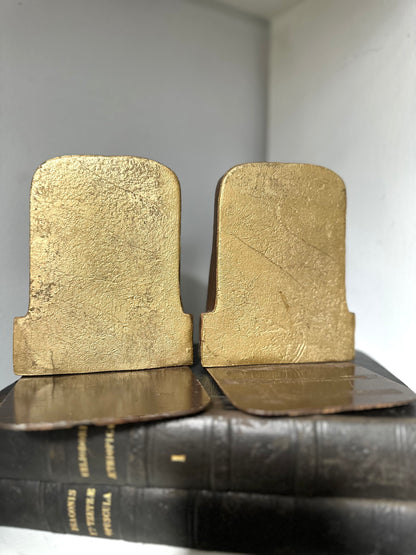 Pair of gold bookends on a black leather-bound book