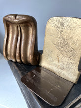 Metallic object with wavy design on a light gray background
