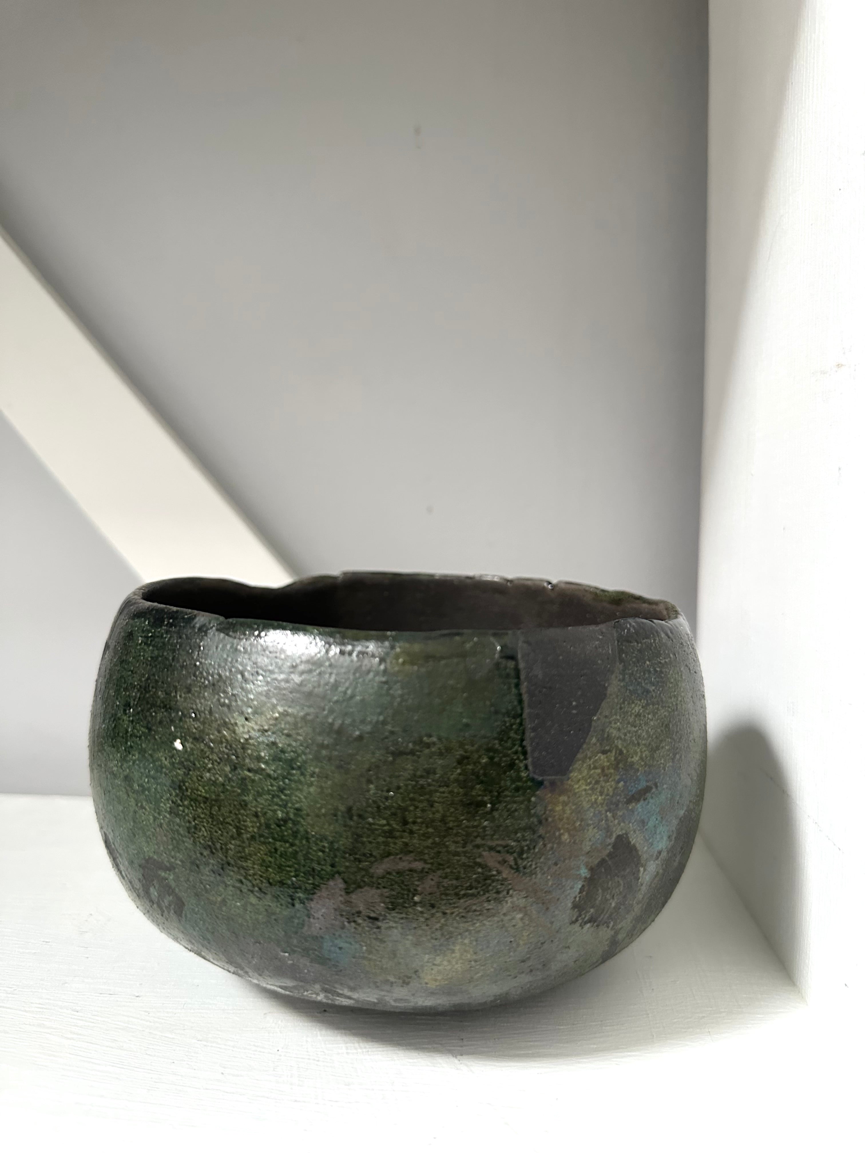 Dark green ceramic bowl on a white surface with a light gray background