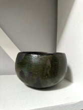 Dark green ceramic bowl on a light gray surface with a white background