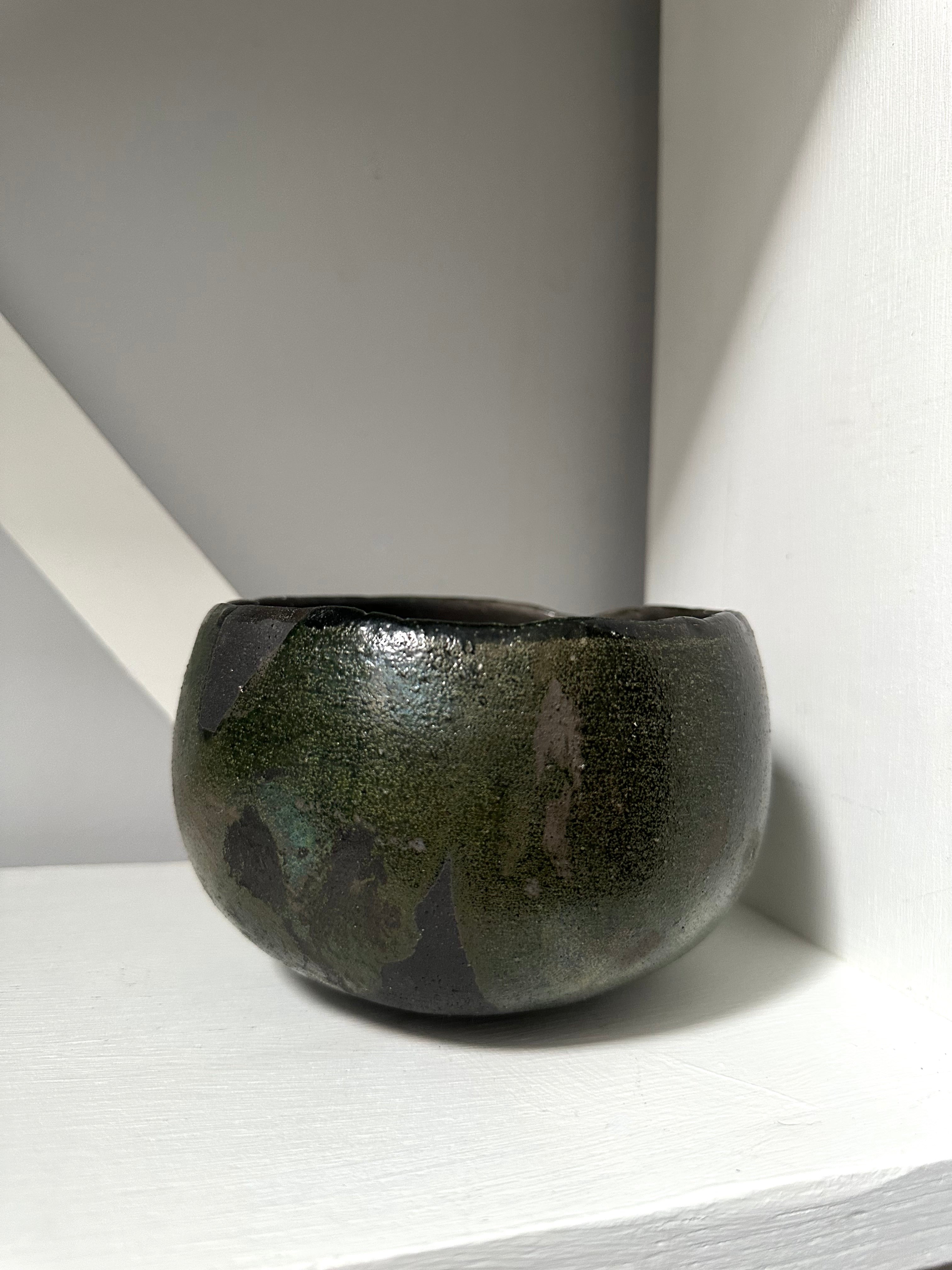 Dark green ceramic bowl on a light gray surface with a white background
