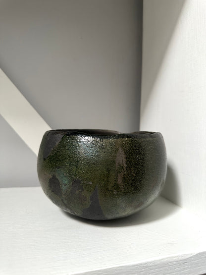 Dark green ceramic bowl on a light gray surface with a white background