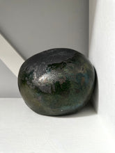 Black stone object on a white surface with a neutral background