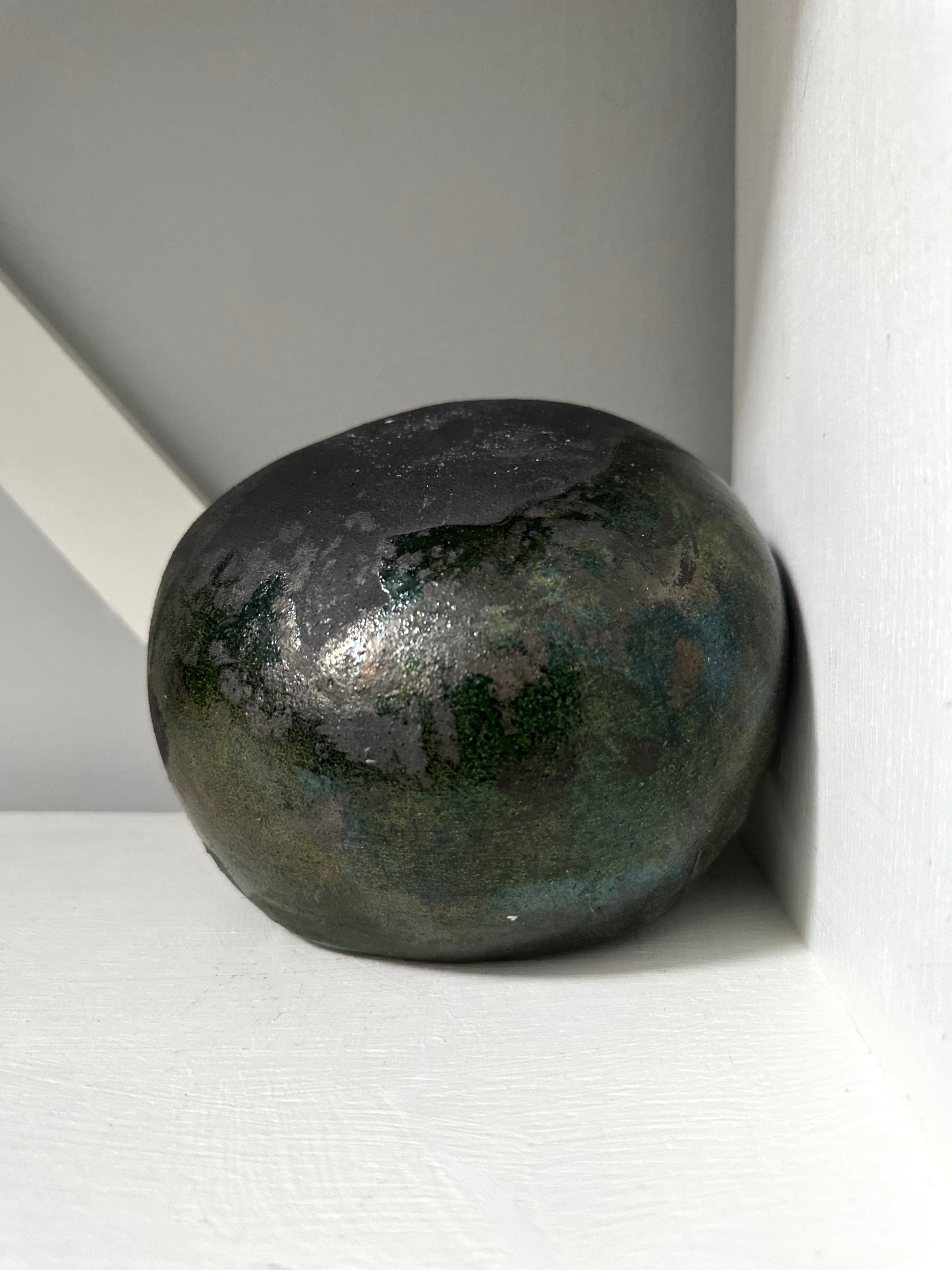 Black stone object on a white surface with a neutral background